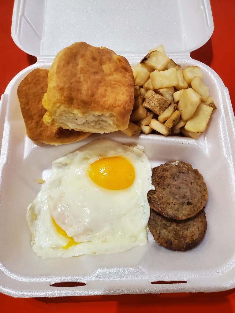 Breakfast plate with a fried egg, sausage patties, biscuits and potatoes